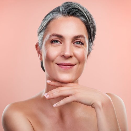 Studio portrait of a beautiful mature woman posing against a peach background