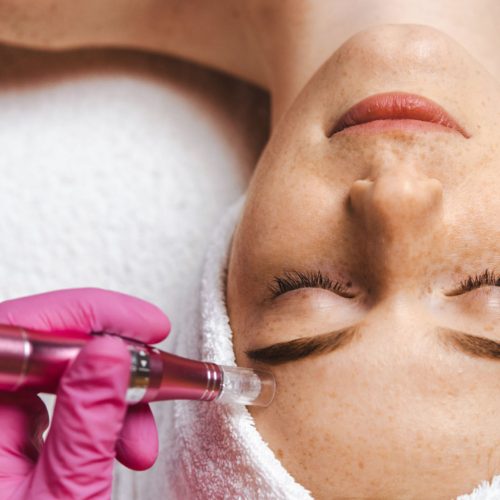 Close-up portrait of cosmetologist beautician's hands doing mesotherapy with dermapen. Microneedle facial procedure. Professional cosmetology.